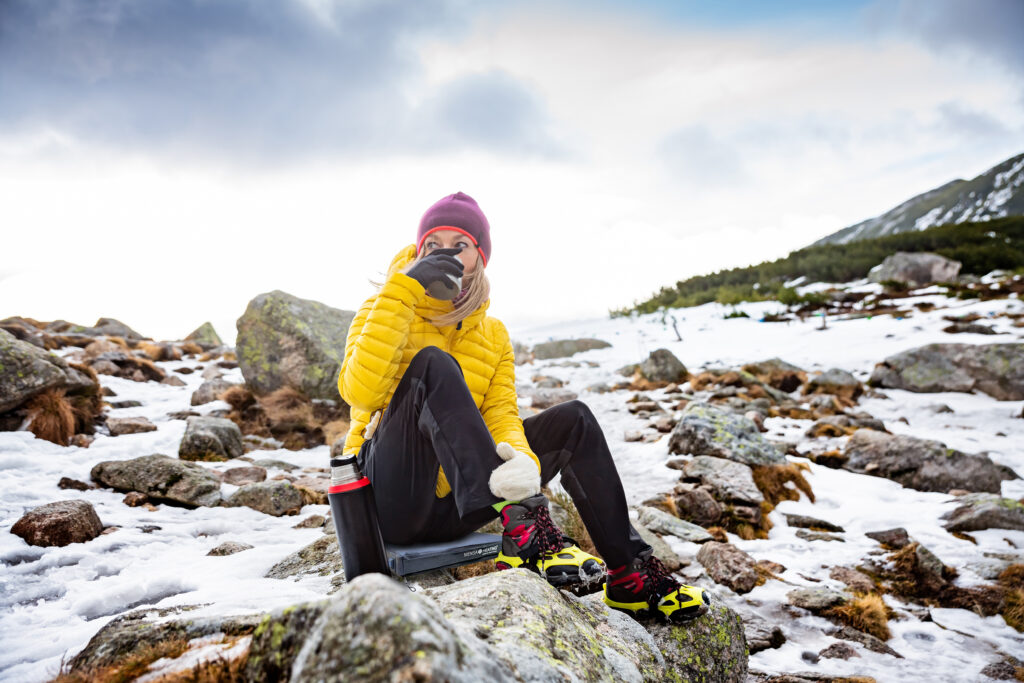 A woman traveler resting and drinking hot tea on a cold, windy day.