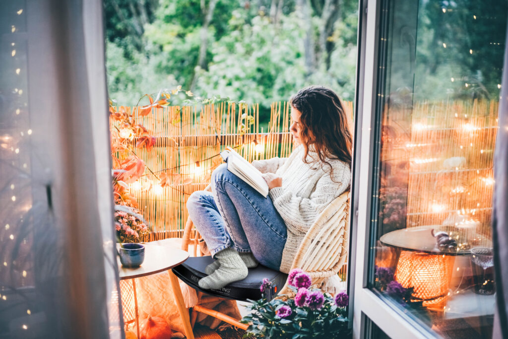 Woman relaxing on cozy balcony, reading a book.